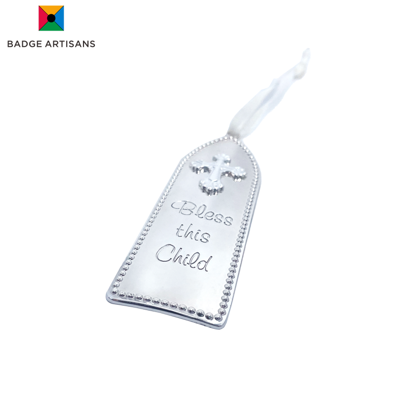 Close-up of silver zinc alloy baptism ornament with beaded border and engraved 'Bless this Child' text, showcasing fine religious keepsake craftsmanship.